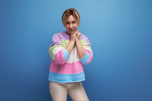 smiling blond woman in casual outfit on blue background with copy space