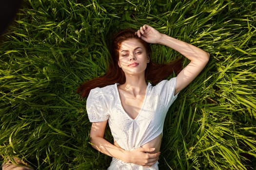 a woman in a light dress lies in tall grass in warm lighting
