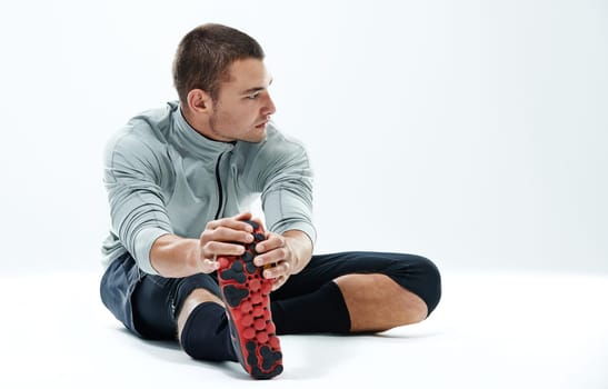 I can see fitness coming. a young man sitting in a studio while doing stretches