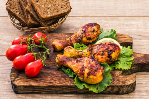 Grilled chicken legs roasted on the grill and lettuce leaves on cutting board