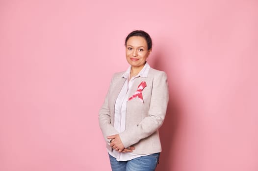 Positive woman, wearing pink satin ribbon, showing her support for Cancer patients. Breast Cancer Day Awareness campaign