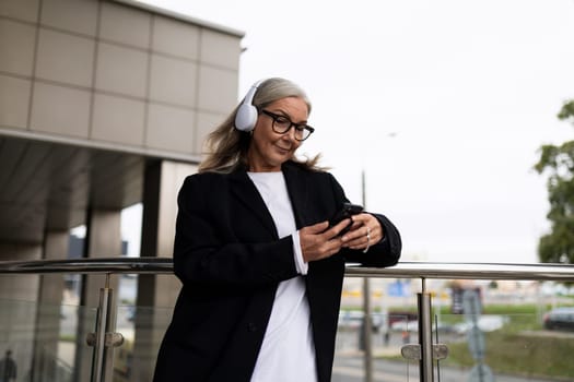 woman economist for contract and claim work, in headphones on the terrace of the office outside answering messages on a mobile phone, investment analysis and valuation models to support the rationale for investment concept