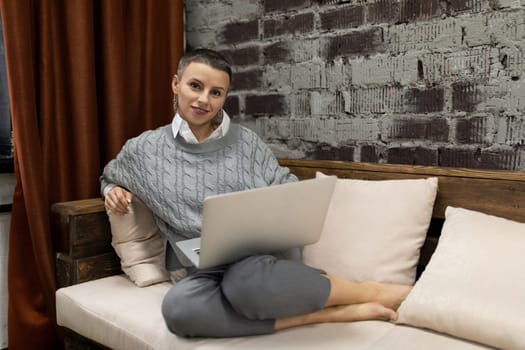 adult woman with laptop on her lap sitting on sofa at home