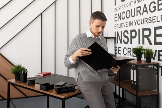 Business woman reading a report in a leather folder on the desktop in the office