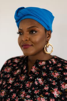 Portrait of cheerful african american woman with headscarf turban against white wall. Happy smiling lady wearing traditional african scarf