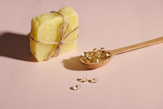Still life with bar of homemade organic cold-pressed soap or solid dry shampoo and a wooden spoon with gelatin capsules