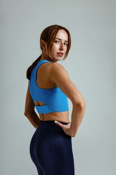 Beautiful fitness woman standing with hands on waist over studio background. High quality photo