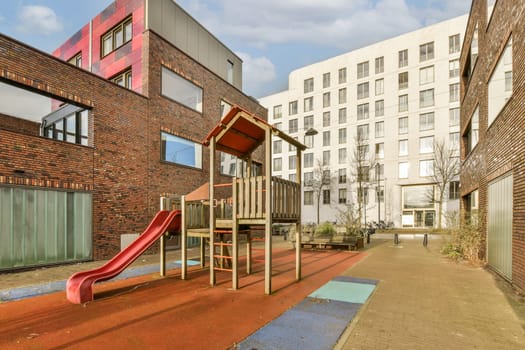 a playground with a red slide on a brick building