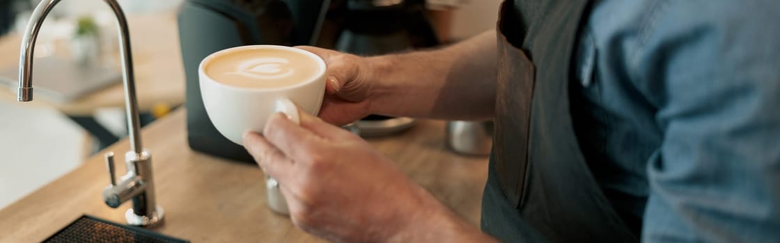 Barista hands holding white cup of coffee