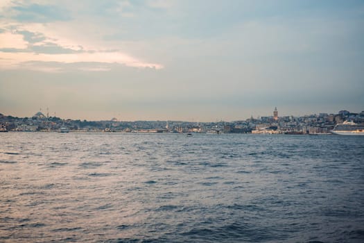 Istanbul at sunset, Turkey. Tourist boat sails on Golden Horn in summer. Beautiful sunny view of Istanbul waterfront with old mosque. Concept of travel, tourism and vacation in Istanbul and Turkey. Turkiye