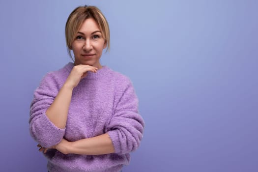 portrait of charming cute blondie woman in casual sweater on purple background with copy space