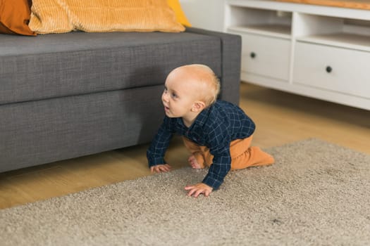 Nursery baby boy crawling on floor indoors at home copy space and empty space for text - Baby curiosity and child development stages