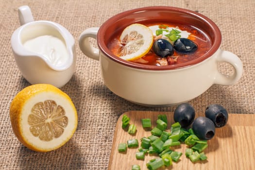 Soup saltwort with meat, potatoes, tomatoes, lemon and black olives in a bowl