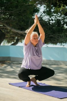 Mature old woman with dreadlocks practicing yoga and tai chi outdoors - wellbeing and wellness