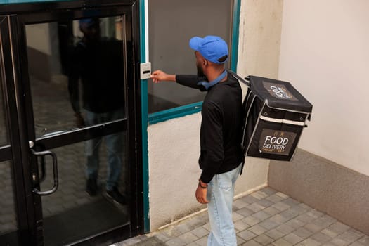 Food deliveryman ringing office building doorbell