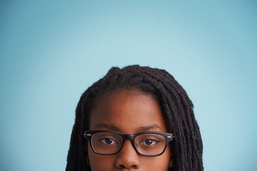 Dont mess with this geek. Cropped portrait of a young boy wearing glasses against a blue background.