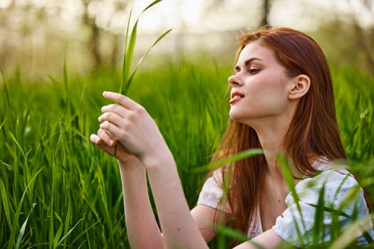 pensive woman with red hair sits in tall grass