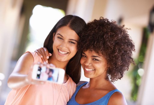 All smiles when friends hang out. two girlfriends taking a selfie on a mobile phone.