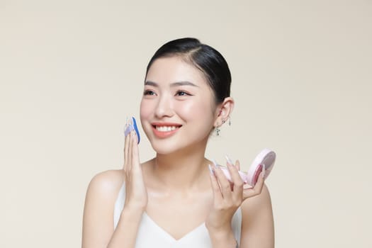 Portrait Of Young Woman Putting Makeup Powder With Cosmetic Cushion On Her Facial Skin
