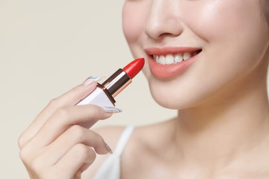 Portrait of gorgeous smiling woman holding red lipstick in hand