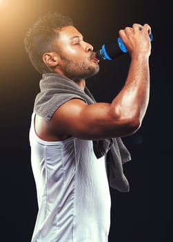 Rehydrating after an epic workout. Studio shot of a fit young man isolated on black.