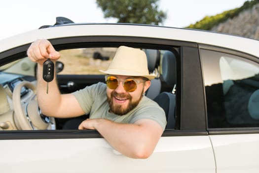 Handsome happy man showing key of new car - Rental and buy new car concept