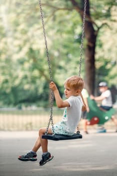 Child on playground. Swing Kids play outdoor.