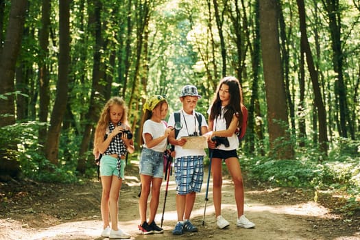 Weekend activies. Kids strolling in the forest with travel equipment
