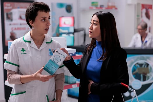Young asian woman explaining gastritis symptoms to drugstore assistant