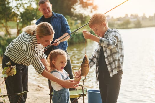Positive emotions. Father and mother with son and daughter on fishing together outdoors at summertime.