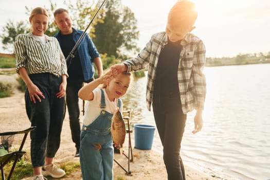 Positive emotions. Father and mother with son and daughter on fishing together outdoors at summertime.