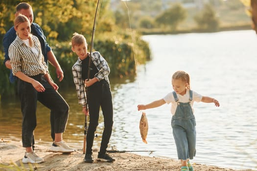 Weekend activities. Father and mother with son and daughter on fishing together outdoors at summertime.