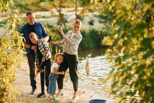 Father and mother with son and daughter on fishing together outdoors at summertime.