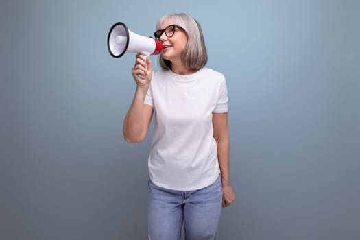 60s woman with gray hair speaks into a megaphone on a studio background