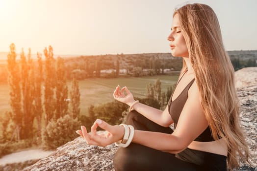 Well looking middle aged woman with long hair, fitness instructor in leggings and tops doing stretching and pilates on the rock near forest. Female fitness yoga routine concept. Healthy lifestyle.