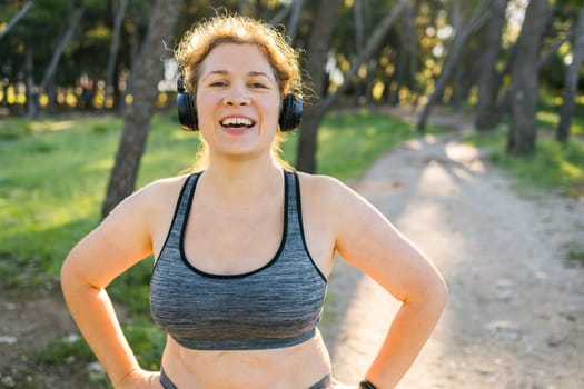 Fat woman and sports. Girl doing exercise for weight loss in the fresh air and laughing in camera after training. Copy space and empty space for text or advertising