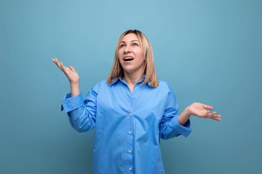 enthusiastic millennial girl in casual look looks up in surprise on a blue background