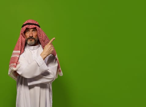 mature Muslim man in a traditional dishdasha points his finger towards copy space symbolizing concept of Sharia law, the Islamic legal system based on teachings of Quran and Hadith. authority, leadership, and principles of justice and ethics within the legal framework of Sharia law, with copy space for additional text or design elements.