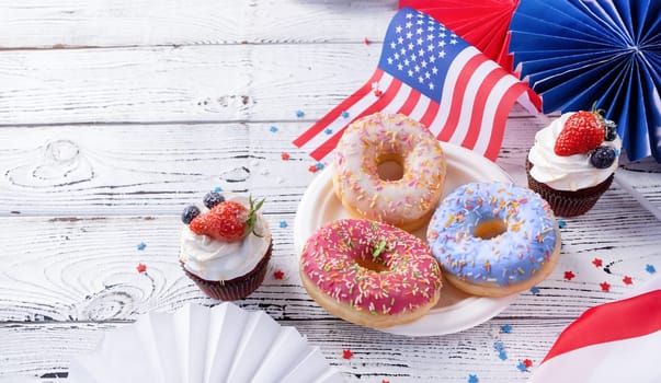 Sweet cupcakes and donuts with usa flag on wooden background