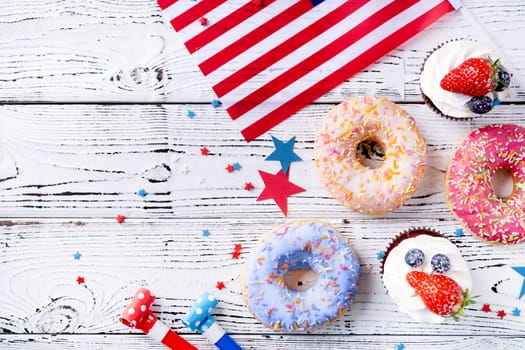 Sweet cupcakes and donuts with usa flag on wooden background
