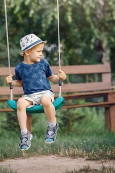 Little boy playing on swing in backyard at countryside