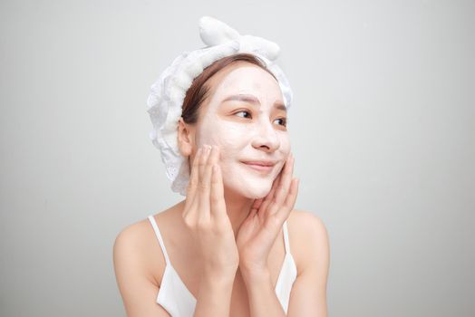 Young attractive Asian woman with white facial clay mask. Beauty spa concept