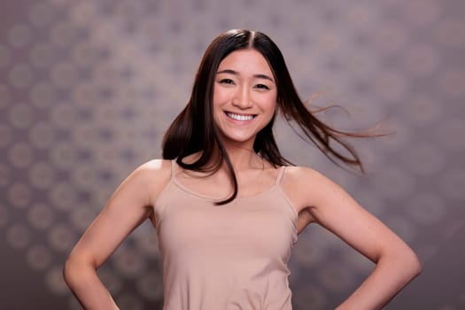 Smiling asian woman with fluttering smooth healthy brown hair