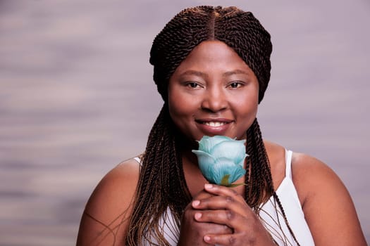 Body positive african american woman posing with blue rose