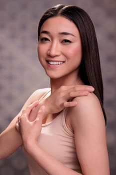 Asian woman touching shoulder and showing body care concept