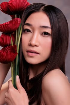Woman leaning red flowers to fresh hydrated skin portrait