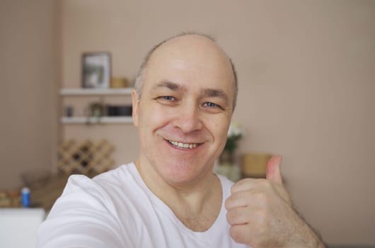 Smiling male blogger taking a selfie or video call from his apartment