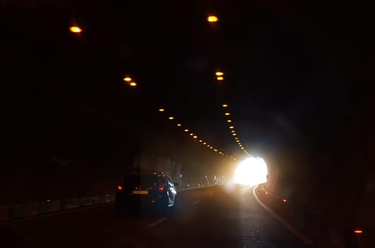 A car is moving towards the exit of the tunnel.