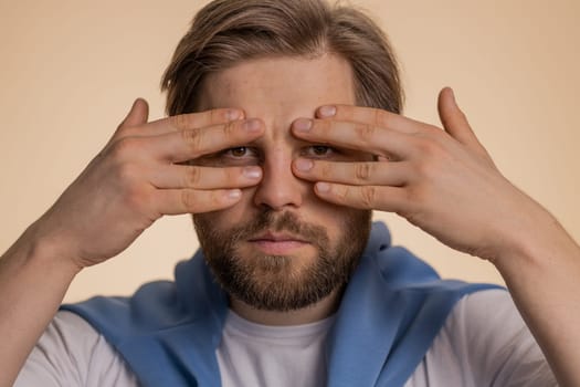 Curious caucasian man closing eyes with hand and spying through fingers, hiding and peeping