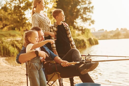 Beautiful nature. Father and mother with son and daughter on fishing together outdoors at summertime.